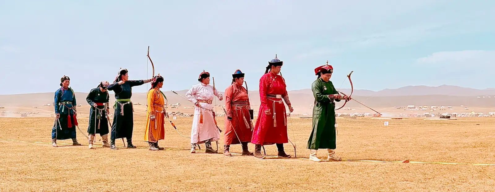 Archers in traditional deel lined up at a Naadam archery competition
