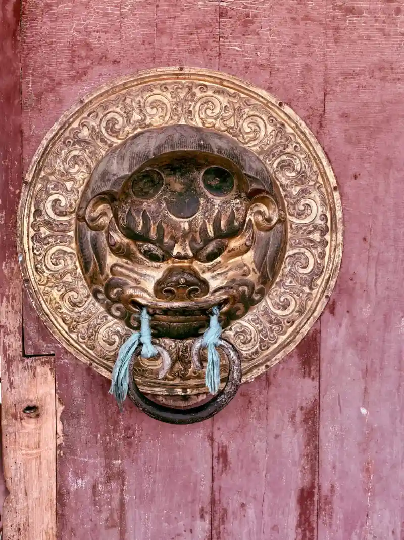 A gilded lion-head door knocker on a red temple door