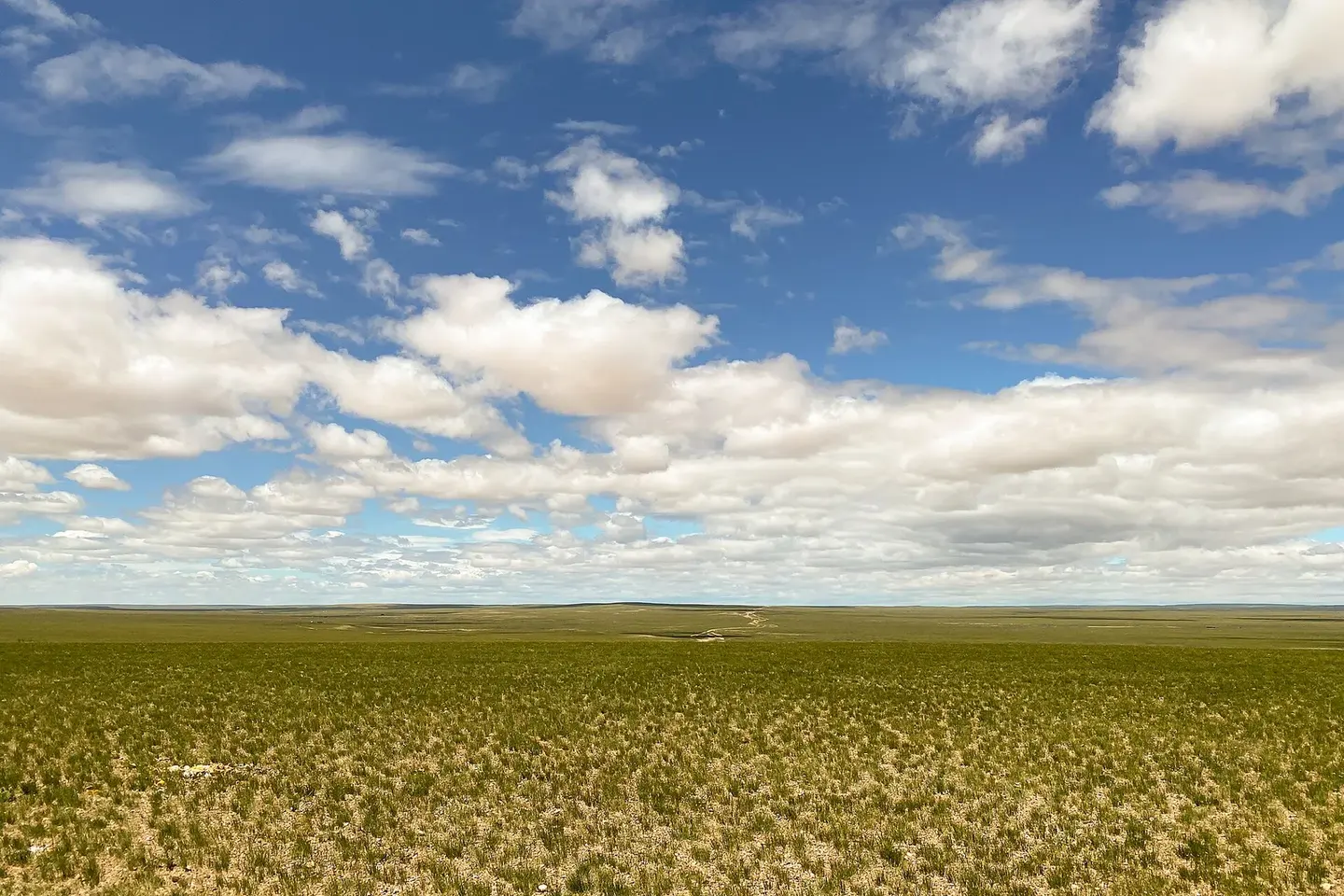 An unpaved track crossing open country toward distant mountains