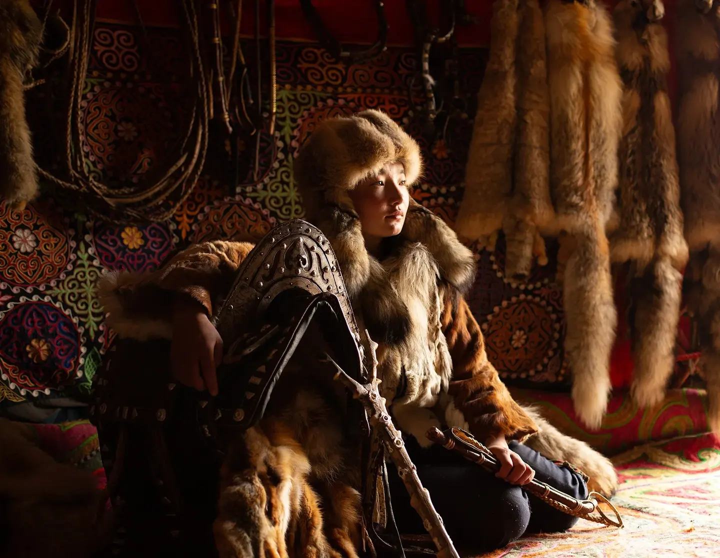 A young Kazakh eagle huntress in traditional dress inside a ger